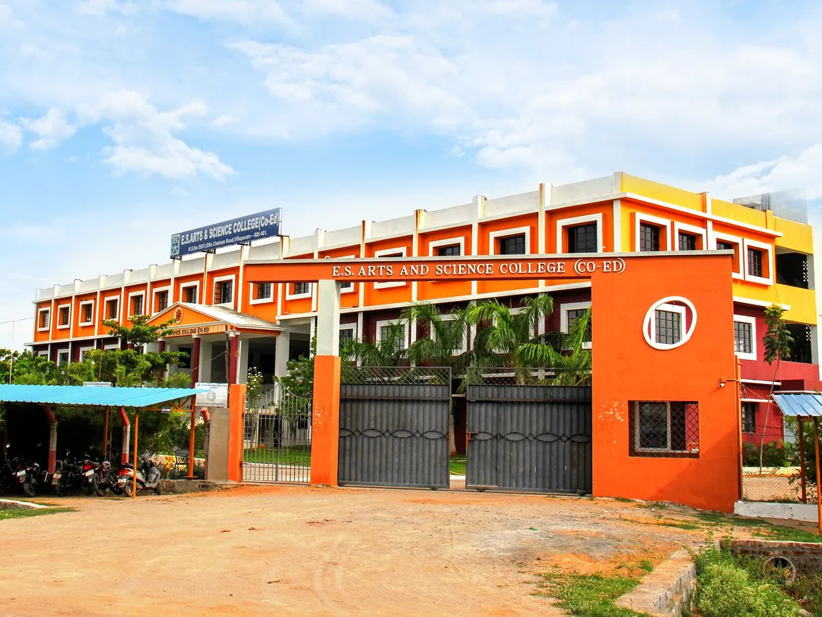 The front gate of E.S Arts and Science College, with the college name across the arch and the orange and yellow college building behind